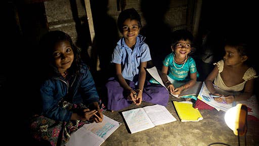 Four young kids share one lamp to finish their homework