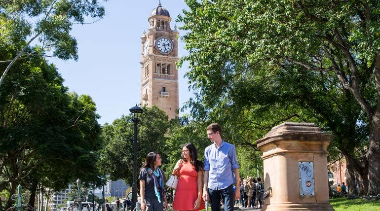 Three students discussing assessment task outside the building